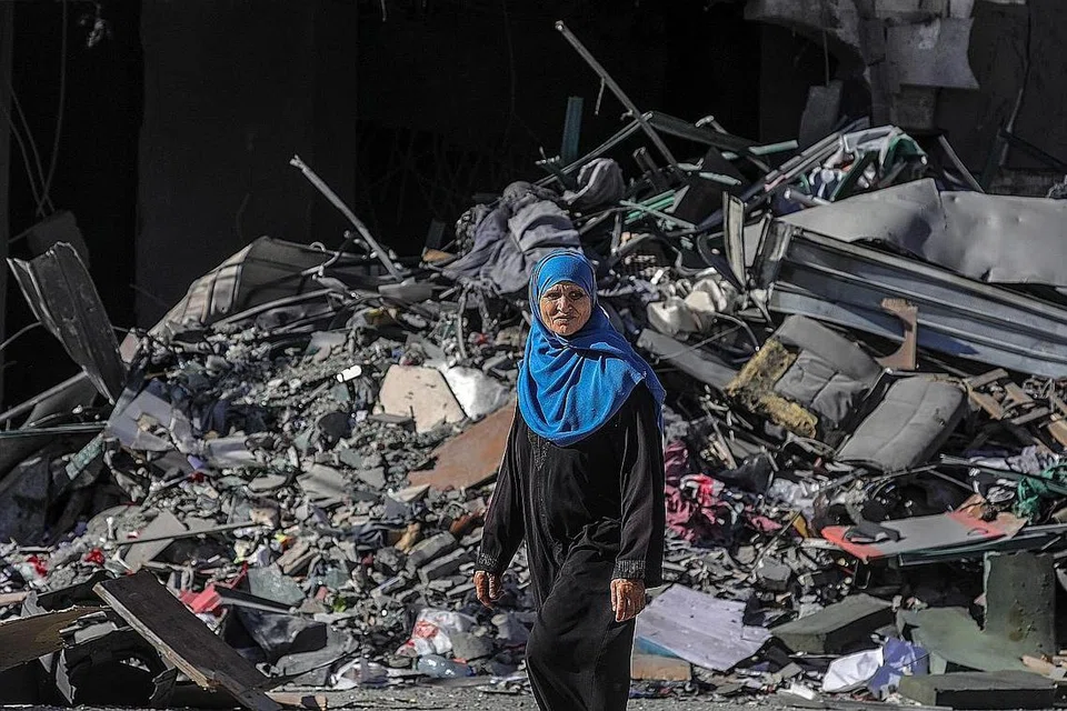 MUSNAH DALAM SEKELIP MATA: Seorang wanita Palestin berjalan di depan sebuah rumah yang musnah dibedil tentera Israel di Kota Gaza, kelmarin. - Foto EPA-EFE