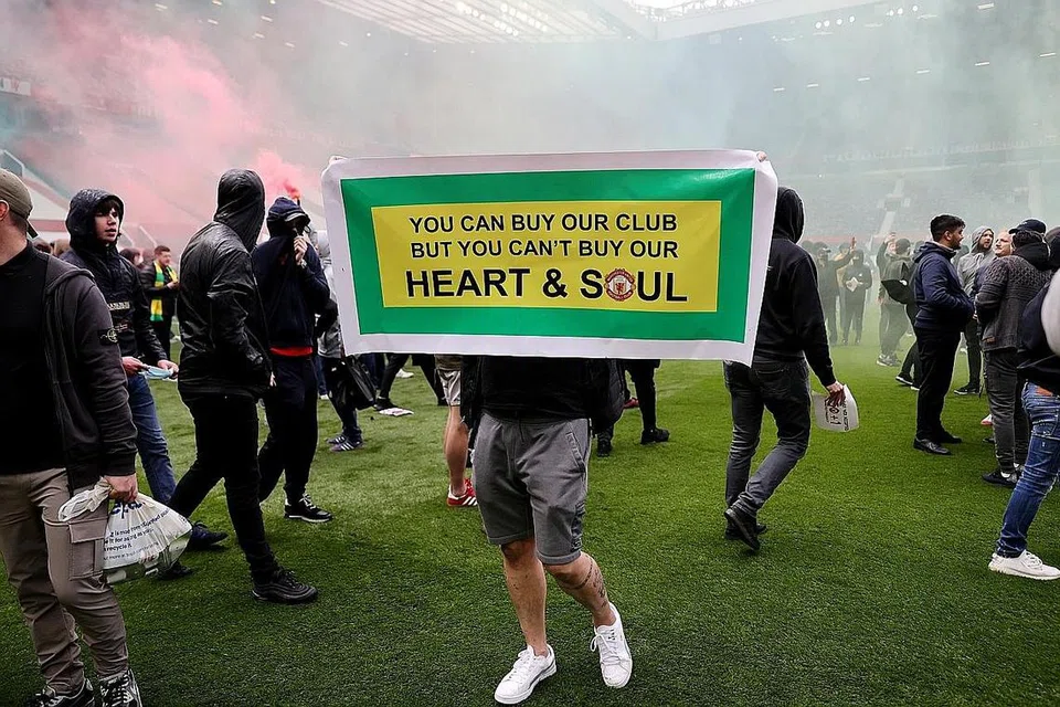 LAKUKAN BANTAHAN: (Gambar atas) Penyokong melakukan protes terhadap pemilik Manchester United di luar dan dalam Stadium Old Trafford dekat Manchester. - Foto REUTERS