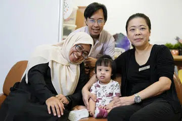 Pada 2023, Cik Adilah Samad (kiri) dan suami, Encik Muhammad Mustaqiim Mukhlis Chan (dua dari kiri), sertai sesi terapi melalui Program Perkhidmatan Sokongan Keluarga Kanak-Kanak dan Remaja (CAFSS) di Hospital Universiti Nasional (NUH) untuk tangani cabaran psikososial menjaga anak mereka, Aafiyah Chan, yang dilahirkan dengan Sindrom Down. Bersama mereka ialah Ketua Psikologi (Pediatrik), Khoo Teck Puat- Institut Perubatan Kanak-Kanak Universiti Nasional (KTP-NUCMI), Cik Ng Siau Hwei. 