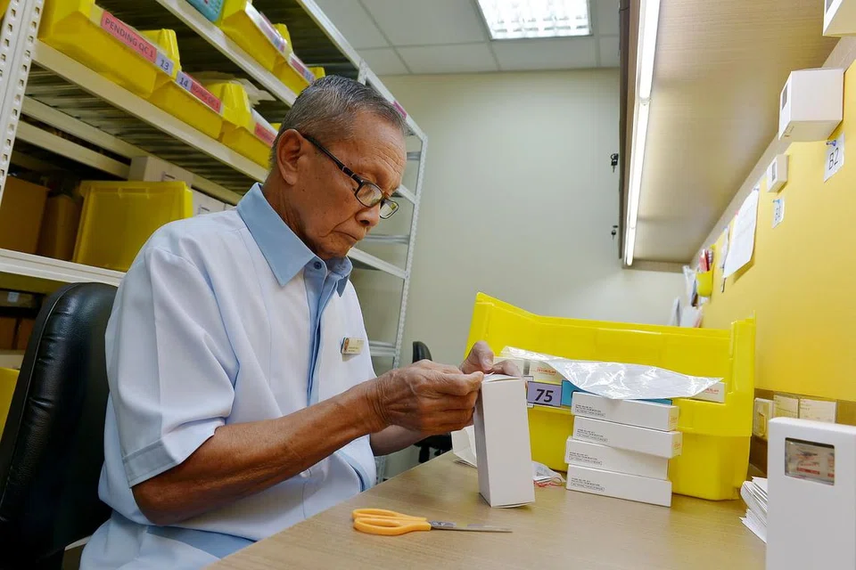 INGIN TERUS MENYUMBANG: Walaupun sudah bekerja hampir seumur hidupnya, Encik Ahmat, yang kini berusia 82 tahun, masih ingin terus menyumbang selagi jasmaninya sihat. Beliau sedang mengasing-asingkan ubat di Poliklinik Hougang.