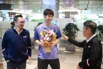 Pemain badminton Singapura, Jason Teh (tengah), disambut Presiden lembaga Persatuan Badminton Singapura, Lawrence Leow (kanan) di Lapangan Terbang Changi ketika beliau pulang ke tanah air pada 3 Februari 2025, selepas menjuarai perseorangan lelaki Thailand Masters.