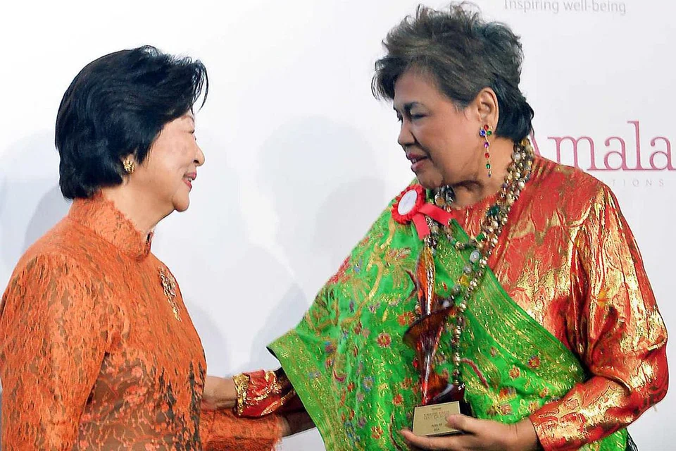 PENGHORMATAN: Cik Aziza (kanan) menerima trofi daripada Cik Mary Tan sebagai salah seorang daripada 14 wanita yang disertakan ke dalam Dewan Kemasyhuran Wanita Singapura (SWHF) tahun ini. - Foto KHALID BABA