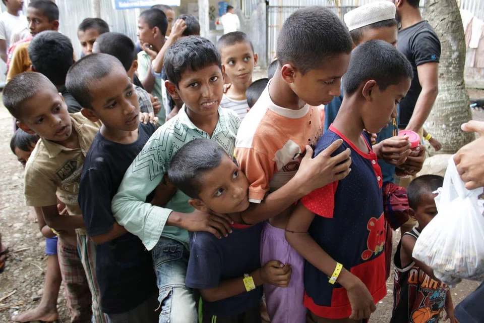 JADI ISU PELARIAN: Gambar yang diambil pada 14 Disember menunjukkan pelarian Rohingya beratur untuk menerima sumbangan di tempat perlindungan sementara di Lhokseumawe, wilayah Aceh Indonesia. 