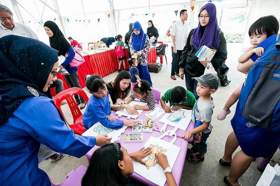 LUANGKAN MASA BERSAMA: Pendidikan merupakan antara fokus M3@Pasir Ris-Punggol, dengan gambar ini menunjukkan ibu bapa dan anak-anak mereka melakukan kegiatan mewarna dalam satu acara yang diadakan. - Foto M³@PASIR RIS-PUNGGOL