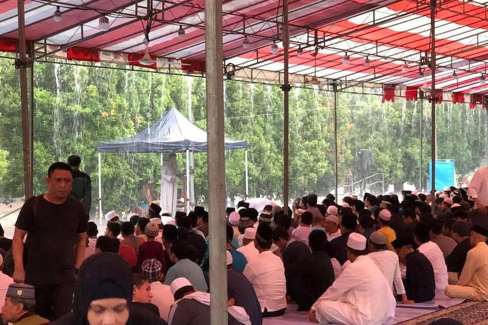 KERJASAMA ANTARA PENDUDUK: Jemaah dapat menunaikan solat Aidiladha dengan sempurna di Blok 630 Bukit Batok Central meskipun hujan lebat dengan khemah yang dipasang Kuil Shen Fu Gong awal.