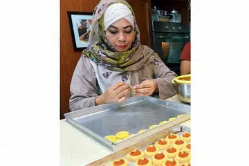 SEPIT SENDIRI: Meskipun jumlah tempahan daripada pelanggan tetapnya boleh mencecah sehingga 10,000 tart setiap musim Hari Raya, Cef Tania masih tetap menyepit doh tart yang ditempah itu secara manual. - Foto-foto KHALID BABA HASIL 