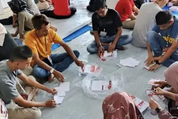 Para relawan melipat kertas undi untuk Pilihan Raya Wilayah 2024 pada 4 November 2024 di gudang Komisi Pemilihan Umum (KPU), Kota Pariaman, Sumatera.