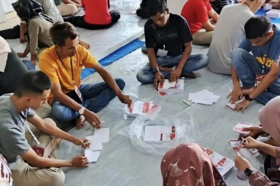 Para relawan melipat kertas undi untuk Pilihan Raya Wilayah 2024 pada 4 November 2024 di gudang Komisi Pemilihan Umum (KPU), Kota Pariaman, Sumatera.