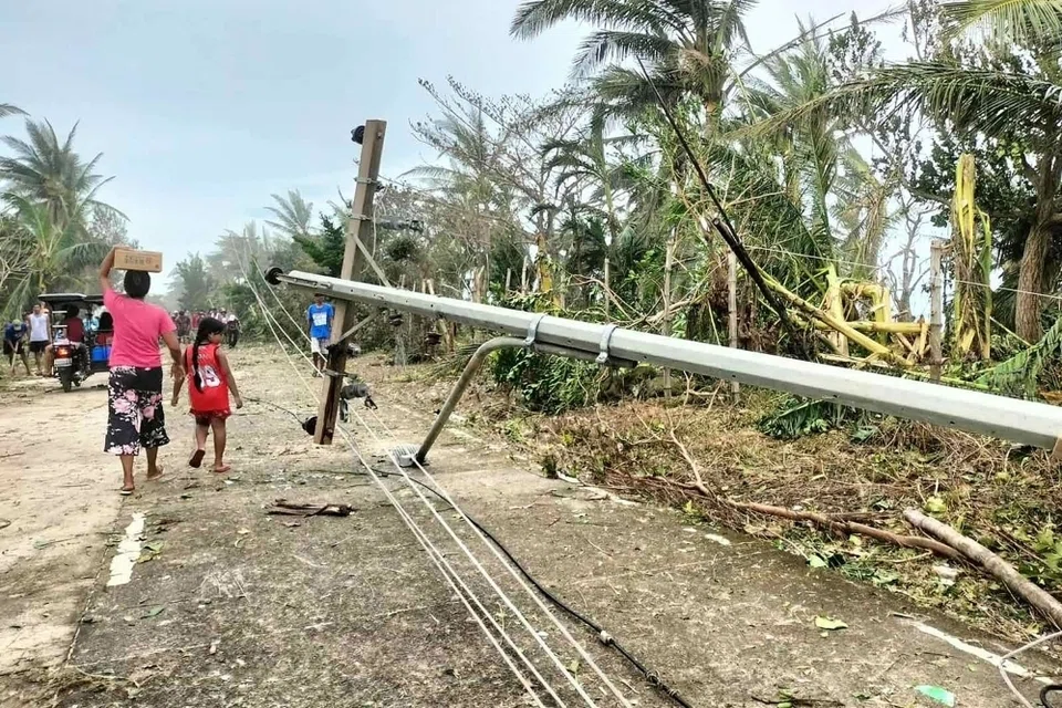 Penduduk berjalan melepasi tiang elektrik yang tumbang di sepanjang jalan di Pulau Calayan, wilayah Cagayan pada 23 September 2025, sehari selepas Taufan Ragasa melanda pulau itu. Ribut Tropika Kuat Bualoi diramal bertambah kuat menjadi taufan pada Jumaat, 26 September dan kemudian menghentam bahagian selatan pulau terbesar Filipina, Luzon.
