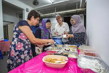SEDIAKAN MAKANAN: Cik Rosiah Hussen (dua dari kiri) berganding bahu dengan beberapa penduduk di kejiranannya untuk menyediakan jamuan iftar kepada sesiapa yang berminat. - Foto BH ZALEHA ABDUL KADER
