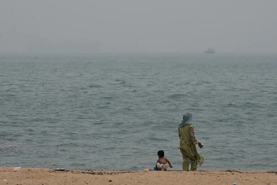 Sepasang ibu dan anak sedang bermain di pantai East Coast pada 16 Oktober. Orang ramai dinasihati agar mengurangkan kegiatan di luar semakin jerebu memburuk di Singapura.