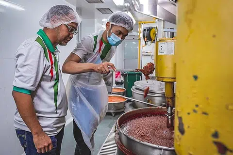 BERSEDIA UNTUK PASARAN EKSPORT: Encik Norhashim (kiri) melihat pekerjanya membuat pes di kilang mereka yang terletak di Admiralty Food Exchange. - Foto BH oleh NUR DIYANA TAHA