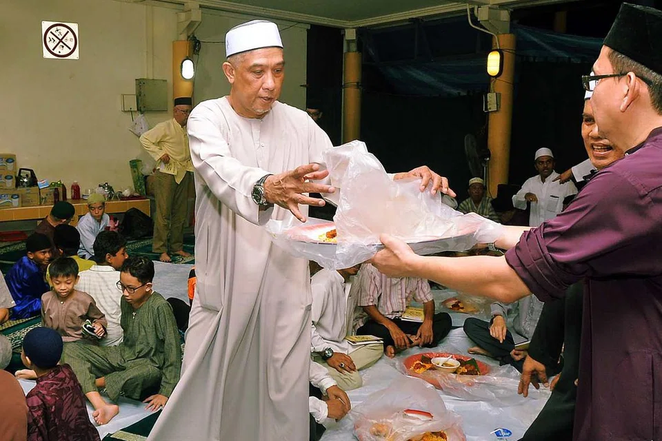 ERATKAN HUBUNGAN: Encik Abdul Rashid menyiapkan juadah untuk dijamu bersama oleh jemaah di kolong Blok 647B Jurong West Street 61 selepas selesai solat tarawih. - Foto KHALID BABA