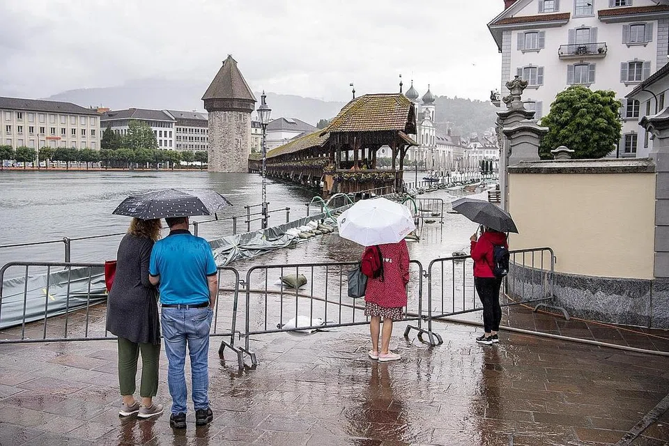 IKLIM GLOBAL MEMBIMBANGKAN: Orang ramai menyaksikan air sungai Ruess melimpah di Lucerne, Switzerland, pada 16 Julai. - Foto EPA-EFE
