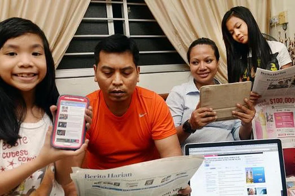 SEKELUARGA BACA BERITA HARIAN: (Dari kiri) Rania Aqilla bersama ayahnya, Encik Ridzwan Idris; ibunya, Cik Rahana Worie; dan kakaknya, Rifqa Nabilla; kini boleh menikmati 'Berita Harian' dalam pelbagai platform, termasuk di laman BeritaHarian.sg, aplikasi BH di telefon bijak dan iPad, selain akhbar cetak. - Foto TAUFIK A. KADER