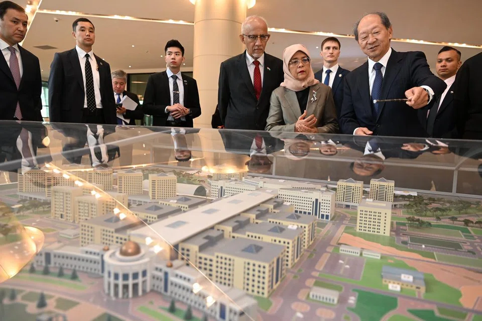 KUNJUNGAN UNIVERSITI: Encik Shigeo Katsu, Presiden Universiti Nazarbayev (dua dari kanan) menunjukkan model kampus kepada Presiden Halimah Yacob (empat dari kanan) dan suaminya, Encik Mohammed Abdullah Alhabshee (lima dari kanan) pada Selasa.