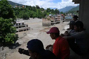Penduduk melihat dari atas bumbung ketika rumah-rumah ditenggelami lumpur tebal selepas banjir kilat melanda Trishuli di daerah Nuwakot, Nepal, pada 27 Ogos. Pasukan penyelamat sedang mencari lebih 1,300 orang yang masih hilang di kawasan sempadan Nepal-Tibet, termasuk sembilan warga Singapura, selepas banjir dan tanah runtuh mengorbankan sekurang-kurangnya 165 orang serta menghanyutkan seluruh penempatan.