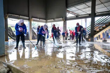BERSIHKAN KAWASAN BANJIR: Sukarelawan Puteri Umno bertungkus lumus membersihkan dewan masyarakat yang terkesan akibat banjir baru-baru ini di Kampung Pengkalan Ajal, Terengganu.