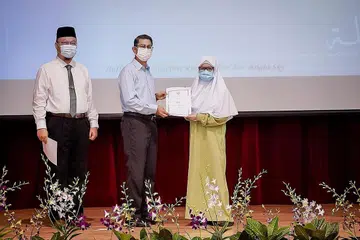 RAIKAN KECEMERLANGAN: Dr Faishal sampaikan anugerah kepada pelajar Nur Syarah Mohamad Rafiz yang menerima Anugerah Kecemerlangan Akademik. Bersama ialah Mudir MAI Encik Herman (kiri). - Foto BM oleh NUR DIYANA TAHA