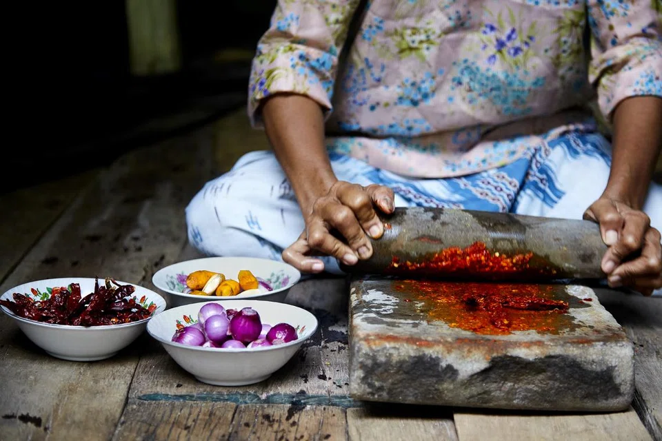 Gambar memaparkan cara membuat sambal cili tradisi asli dengan menggunakan batu giling. 