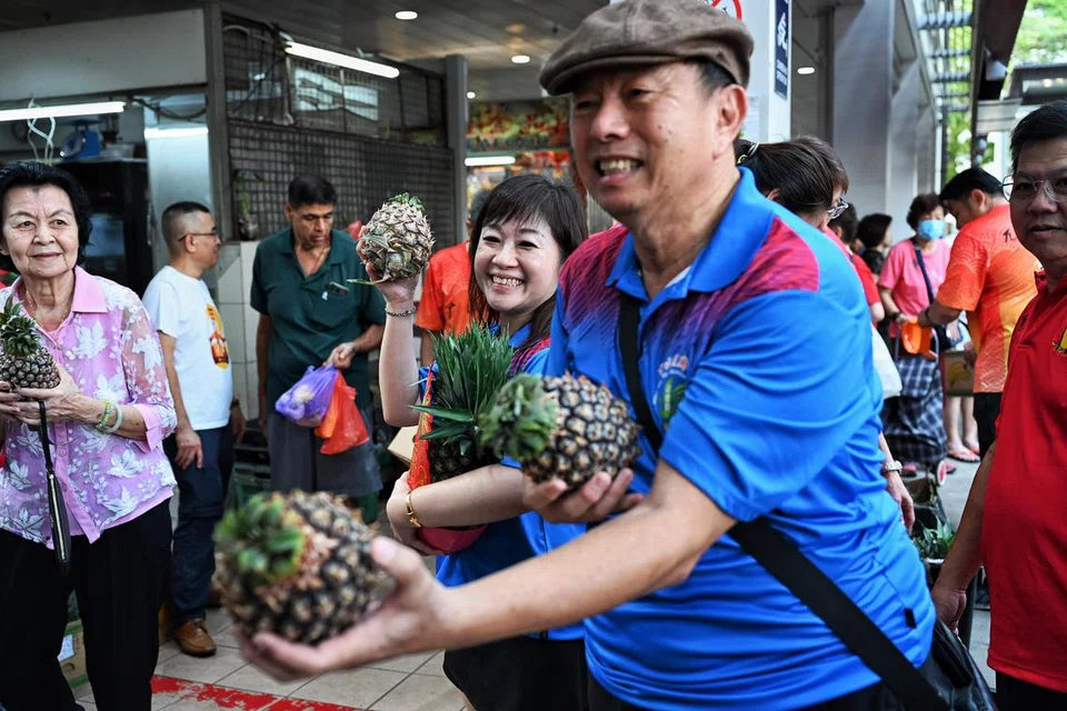 AGIH NANAS: Seorang sukarelawan mengagihkan nanas kepada penyokong yang hadir di Pusat Penjaja Taman Jurong pada pagi Sabtu. 