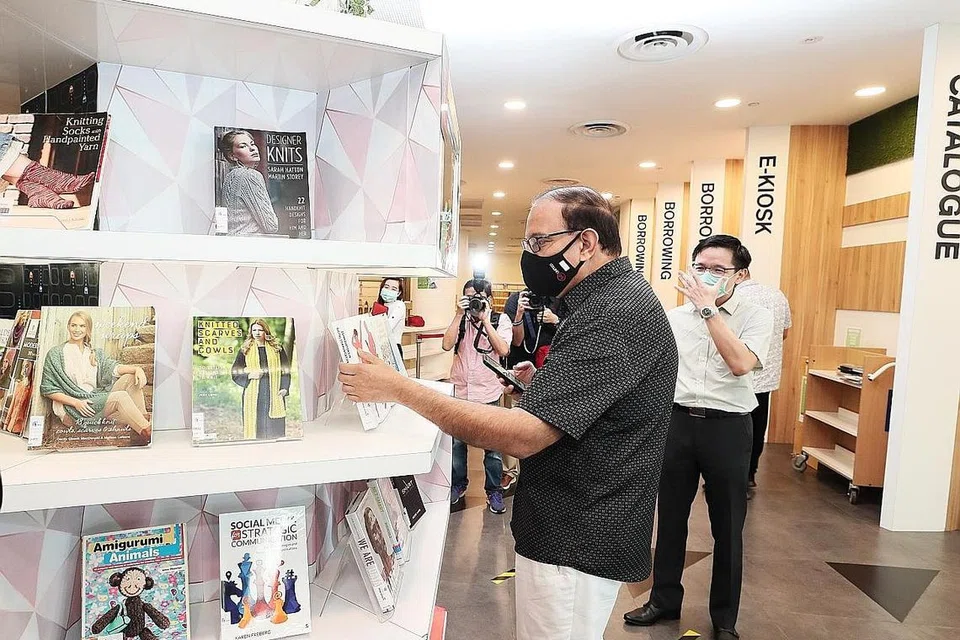 LANGKAH PENCEGAHAN: Semasa lawatan pembukaan semula di Perpustakaan Daerah Jurong semalam, Encik Iswaran (berbaju hitam) mencuba sistem meminjam buku di perpustakaan tanpa sentuhan melalui telefon bimbit dengan Aplikasi NLB untuk mengimbas kod bar, yang tidak memerlukannya ke kaunter pinjaman fizikal sebagai salah satu langkah pencegahan terhadap koronavirus. - Foto BH oleh KELVIN CHNG