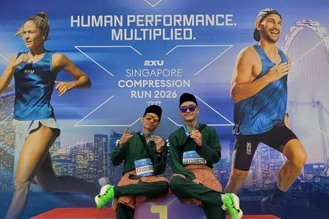 BERBAJU MELAYU: Encik Muhammad Dani Mirza Ahmad Affandi (kiri) dan Encik Muhamad Nurirsyad Azman bergambar di podium setelah selesai berlari dalam acara separuh maraton sejauh 21.1 kilometer, 2XU Compression Run 2026, dengan berbaju Melayu lengkap dengan samping dan songkok.