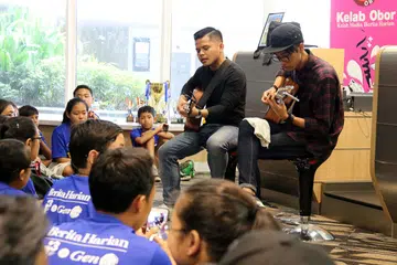HIBURAN SELINGAN: Penyanyi muda setempat, Haikal Ali (kiri) dan Iyaad Salleh, menghiburkan peserta kem sedang wartawan dan pereka laman Berita Harian menilai tugasan yang mereka siapkan.