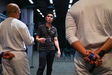 Noor (kiri) dan Hafiz (kanan), bukan nama sebenar, bersama jurulatih muzik mereka, Encik Aaron Lim, yang juga Pengarah Intune Music, membuat persiapan bagi persembahan Konsert Ulang Tahun ke-20 Projek Reben Kuning (YRP) di Kompleks Penjara Changi pada 30 September.