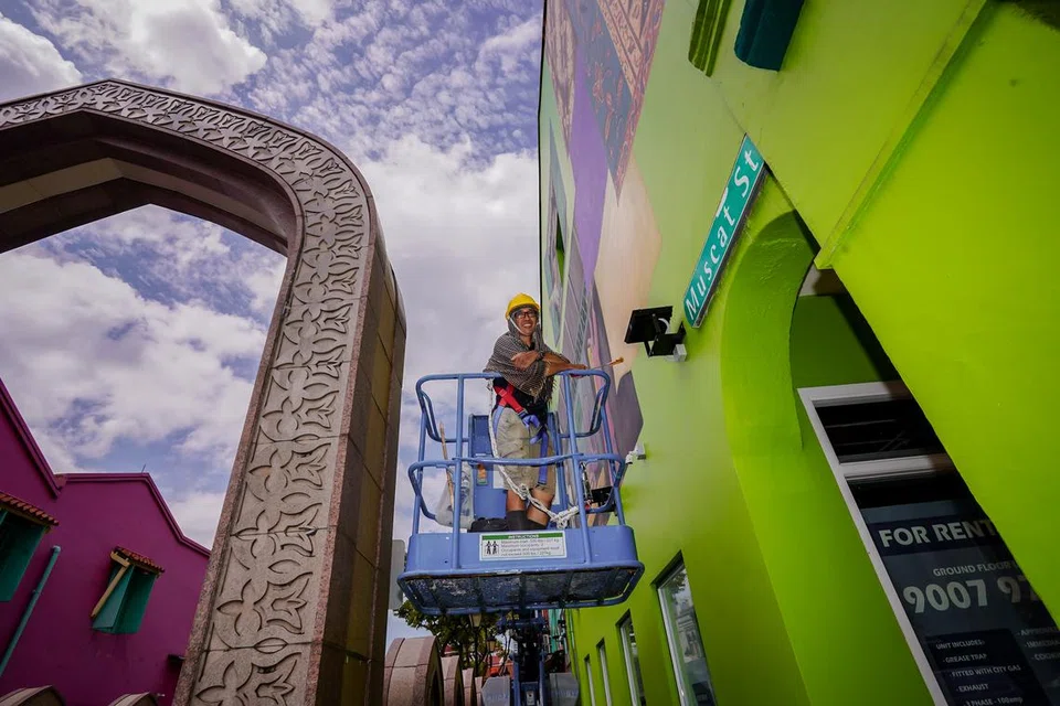 SIBUK BEKERJA: Pelukis Yip Yew Chong sedang sibuk mengusahakan lukisannya di atas kren di Muscat Street.