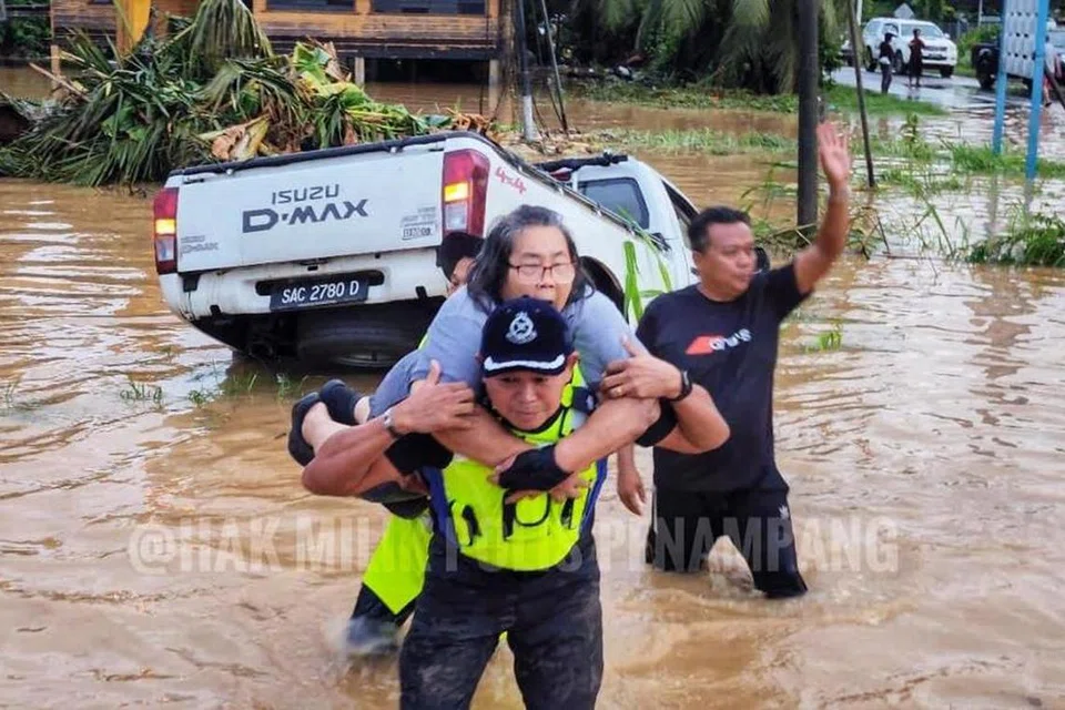 Ketua Polis Daerah Penampang, Superintenden Sammy Newton (depan), menyelamatkan seorang wanita warga emas yang terperangkap dalam kenderaan di kawasan banjir berhampiran Jalan Kasigui, Penampang, Sabah, pada 1 Julai. 