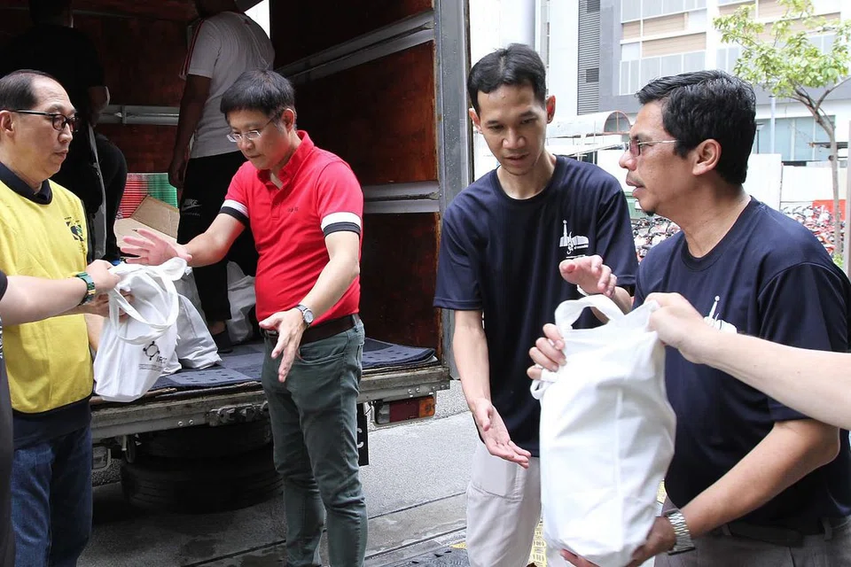 USAHA MURNI: Encik Gan Thiam Poh (berbaju merah) berganding bahu dengan sukarelawan memunggah habuan untuk diedarkan kepada keluarga memerlukan dalam rangka Projek SOS anjuran Masjid Al-Mawaddah dengan kerjasama badan berbilang agama, pertubuhan masyarakat dan belia. - Foto MASJID AL-MAWADDAH