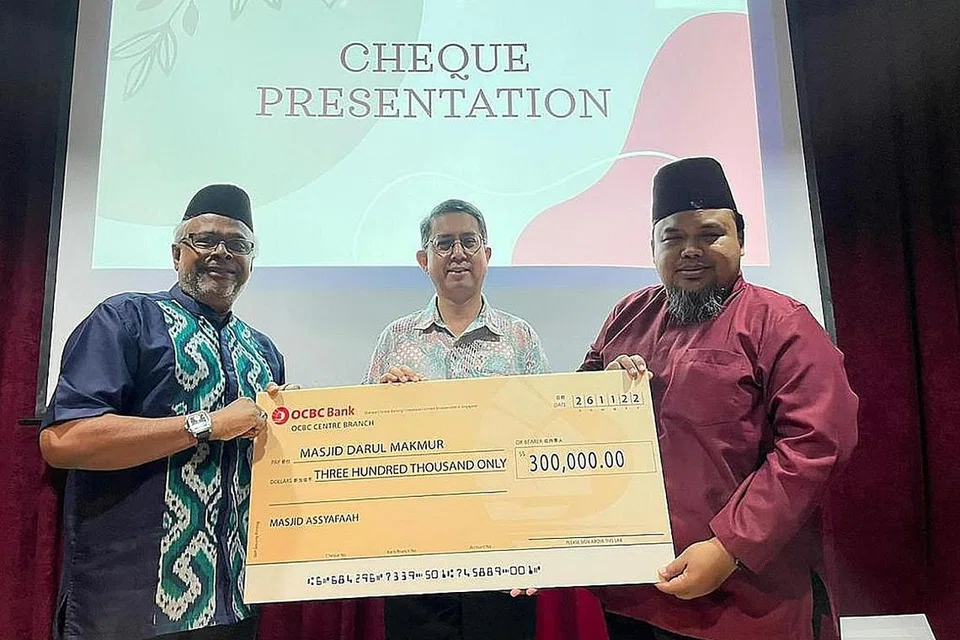 SUMBANGAN CEK BAGI DANA PENINGKATAN: Pengerusi Eksekutif Masjid Darul Makmur, Encik Izuan Mohd Rais (kanan), menerima pemberian cek untuk Masjid Darul Makmur daripada Naib Pengerusi Masjid Assyafaah, Encik Mohd Salleh (kiri), dan beberapa masjid lain di majlis Hari Keluarga baru-baru ini. Turut menyaksikan majlis penyampaian cek itu ialah Menteri Negara (Ehwal Dalam Negeri merangkap Pembangunan Negara), Profesor Madya Dr Muhammad Faishal Ibrahim (tengah), yang turut hadir dalam acara Hari Keluarga itu. - Foto MASJID DARUL MAKMUR.