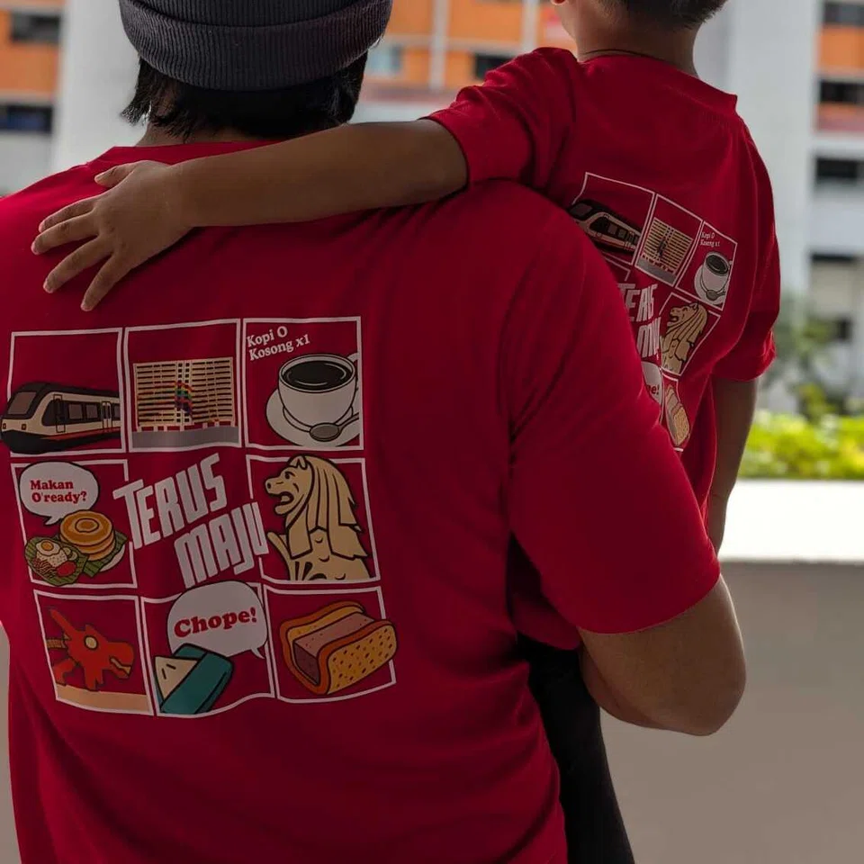 Bahagian belakang baju-T itu memaparkan kolaj kehidupan harian rakyat Singapura. Ini termasuk MRT, deretan flat HDB, budaya menikmati kopi, penjaja aiskrim bermotosikal, makanan penjaja, dan Merlion.