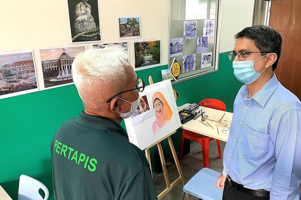 TUNJUK BAKAT: Menteri Negara (Ehwal Dalam Negeri merangkap Pembangunan Negara), Prof Madya Dr Muhammad Faishal Ibrahim, didedahkan dengan bakat melukis seorang penghuni Rumah Peralihan Pertapis semasa mengadakan lawatan pada 25 September tahun lalu. - Foto PERTAPIS HWH