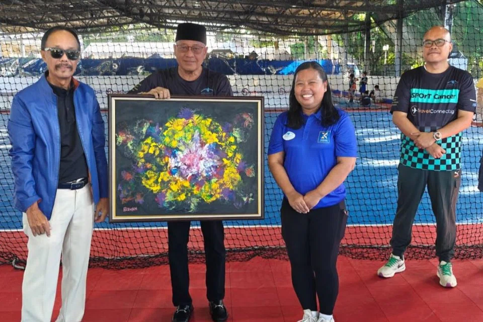 MEMBANTU PESAKIT BARAH: Cikgu Sies Senan (kiri)  menyerahkan kepada CEO Persatuan Ain, Encik Md Yusof Ismail, salah satu daripada empat lukisan koleksi beliau yang dibeli CEO Sheng Siong, Encik Lim Hock Chee, dan didermakan kembali kepada persatuan itu. Bersama mereka ialah Anggota Parlimen GRC Sembawang, Cik Mariam Jaafar. 