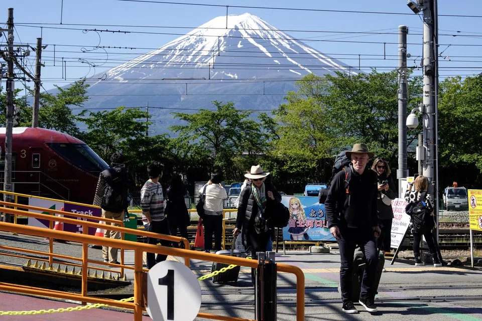 Pelancong asing tiba di stesen Kawaguchiko dengan latar belakang Gunung Fuji. Wilayah Yamanashi telah memperkenalkan tempahan secara dalam talian bagi sesiapa masuk ke kawasan gunung itu menerusi Laluan Yoshida. 