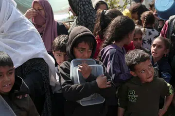 Penduduk termasuk kanak-kanak Palestin berkumpul untuk mendapatkan makanan di Rafah, selatan Semenanjung Gaza pada 28 Februari 2024, di tengah-tengah pertempuran berterusan antara Israel dengan Hamas.