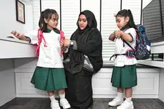 SIAP UNTUK KE SEKOLAH: Kembar, Nur Hifza Safiyyah Mohamed Hamzah (kiri) dan Nur Hafsa Safiyyah Mohamed Hamzah dibantu ibu mereka, Cik Nur Jannah Abdul Jalil, ketika mencuba pakaian seragam dan beg sekolah baru sebagai persediaan memasuki Darjah Satu.
