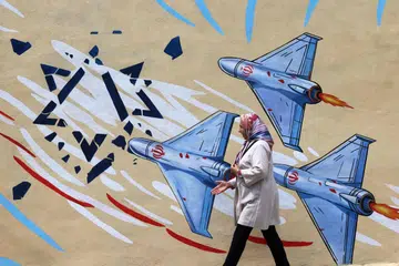 Gambar yang dirakam pada 8 April 2026 menunjukkan seorang wanita berjalan melepasi mural anti-Amerika Syarikat dan anti-Israel di Teheran. Sejak tercetusnya perang antara Iran, Israel dan Amerika Syarikat, mural berwarna-warni mula muncul di seluruh Teheran dan kawasan sekitarnya, sarat dengan simbolisme serta tema penentangan dan keberanian.
Mural dan sepanduk telah lama menjadi ciri utama landskap bandar di Iran, khususnya di Teheran, di mana lukisan di dataran utama sering mencerminkan mesej politik kerajaan serta pendirian dasar luar negara itu.