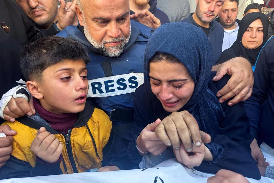 MANGSA PEPERANGAN: Pengarang Aljazeera, Encik Wael Al-Dahdouh, mendakap anak perempuan dan anak lelakinya di upacara pengebumian anaknya, Encik Hamza Al-Dahdouh, seorang wartawan yang terbunuh dalam serangan Israel di Rafah, selatan Gaza.