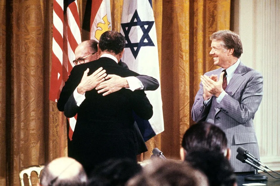 Pada 17 September 1978, Presiden Mesir Anwar al-Sadat (kiri) dan Perdana Menteri Israel Menachem Begin berpelukan selepas menandatangani perjanjian damai bersejarah di Rumah Putih. Upacara tersebut disaksikan oleh Presiden Amerika Syarikat ketika itu, Encik Jimmy Carter (kanan), yang memainkan peranan penting dalam rundingan tersebut.