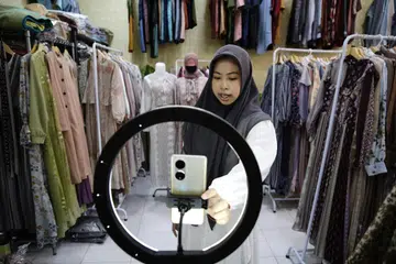 TIADA SAINGAN: Seorang peniaga di Depok dilihat menggunakan telefon bimbit untuk memasarkan pakaian jualannya menerusi platform e-dagang. 