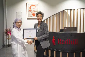 Pengurus operasi Redhill, Cik Fauziah Palil (kiri), menerima saham syarikat daripada Presiden Redhill, Cik Manisha Seewal (kanan), di bawah program Program Pelan Pemilikan Saham Pekerja (ESOP) yang dilancarkan oleh agensi komunikasi sejagat itu pada 1 Mei.