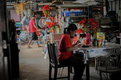 MAKAN SECARA SEDERHANA: Cik Hillary Lee duduk di dapur ladang untuk makan tengah hari yang dibeli dari pusat beli-belah Lot 10 malam sebelumnya, sejuk dan tidak panas kerana ketiadaan microwave.