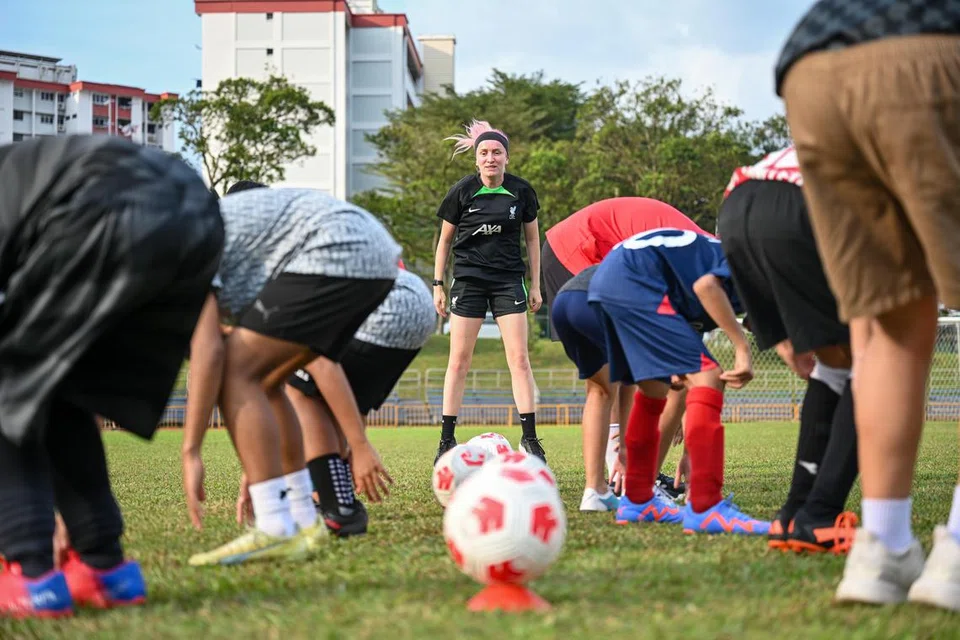 BANTU KANAK-KANAK: Salah seorang kakitangan LFC, Rachel Unsworth (menghadap kamera), giat membimbing para peserta yang terdiri daripada kanak-kanak keluarga berpendapatan rendah di padang bola sepak.