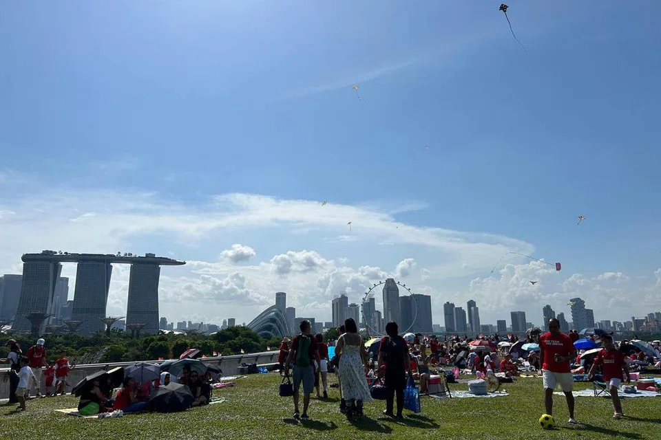 MERIAH: Suasana di Bendungan Marina kelihatan meriah dengan ramai penduduk berkelah dan bersantai sementara menunggu pertunjukan udara RSAF dan ledakan bunga api di Marina Bay.