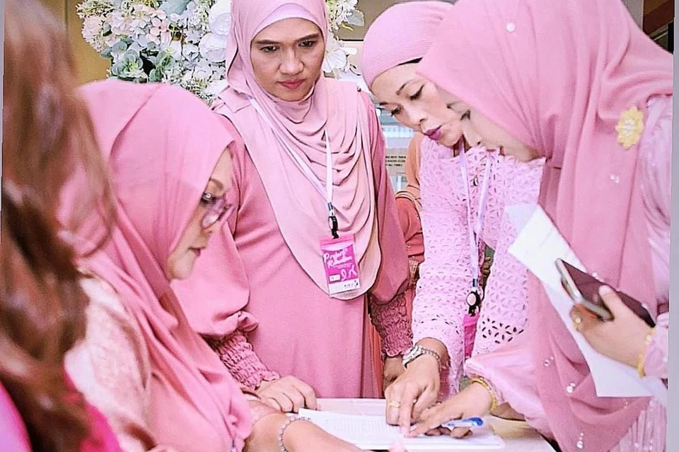 Para sukarelawan dari Women Empowerment Singapura mengenakan pakaian berwarna merah jambu di majlis amal di De Hall, Tai Seng Centre.