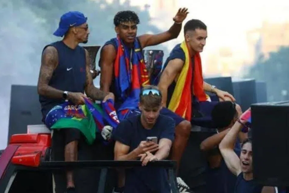 Pemain FC Barcelona, ​​Lamine Yamal (tengah) semasa perarakan bas pada 11 Mei ketika mereka meraikan kemenangan kejuaraan La Liga.