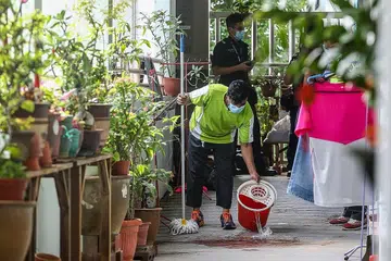 KESAN DARAH: Seorang pekerja membersihkan kesan darah sepanjang koridor di Blok 562 Ang Mo Kio. - Foto ZAOBAO